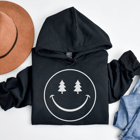 Introducing the latest in outdoor fashion and forest friendliness: the "Tree-mendous Smiles Hoodie"! This isn't just any hoodie; it's your ticket to becoming the most smiley face in the wild. With a dazzling happy face emblazoned on the front, you're set to spread joy among the trees, the birds, and even the most stubborn of rocks.